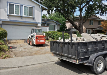 A Bobcat is used to remove driveway rubble as driveway pavers are prepared for.