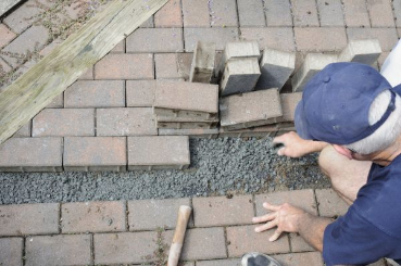 Pavers contractor gently pulls up old stained and broken pavers to be replaced with new ones. 
